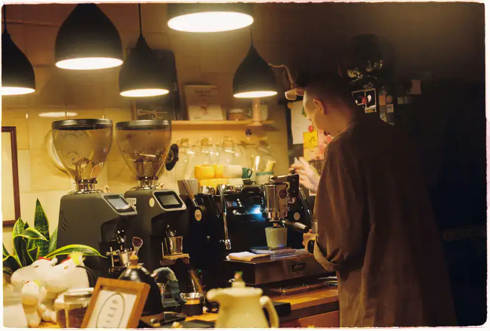 Barista preparing an espresso shot in a warmly lit environment